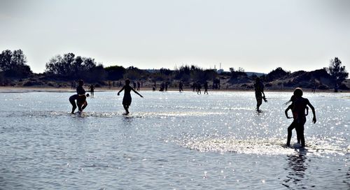 Children playing in water against clear sky