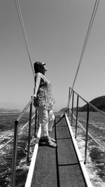 Woman standing by railing against sea