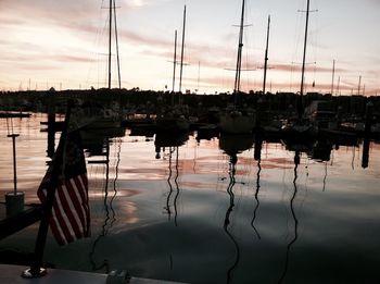 Boats moored in harbor at sunset