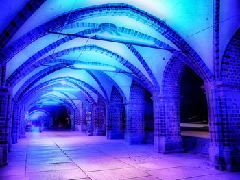 Illuminated footpath amidst buildings at night