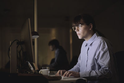 Young businesswoman using computer while working late in office at night