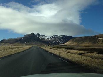 Road amidst landscape against sky seen through car windshield