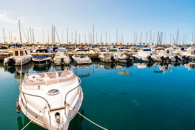 Sailboats moored at harbor against blue sky