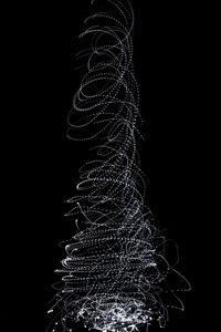 Low angle view of illuminated christmas tree against black background