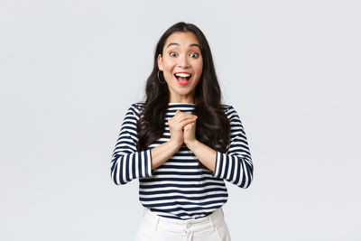 Portrait of young woman standing against white background