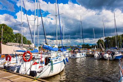 Sailboats moored at harbor against sky