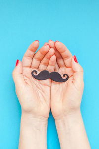 Close-up of human hand holding blue background