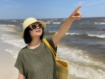 Portrait of young man wearing sunglasses standing on beach