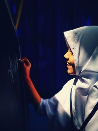 Close-up of girl writing on blackboard