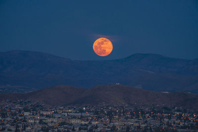 Townscape and mountains against moon at night