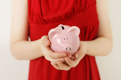 Midsection of girl holding piggy bank