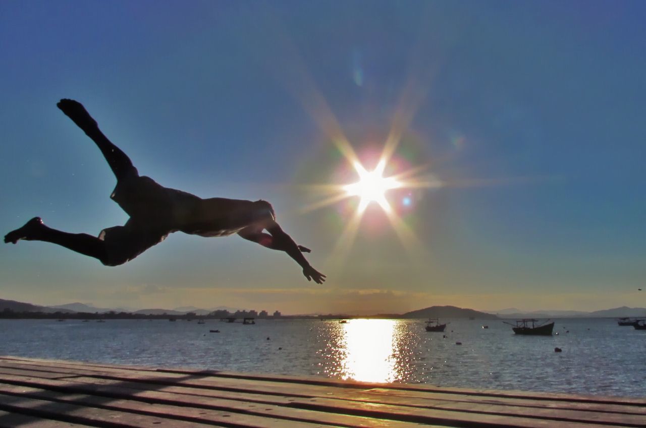 sun, water, silhouette, sea, mid-air, sunset, sky, sunlight, flying, sunbeam, animal themes, full length, jumping, lens flare, lifestyles, leisure activity, horizon over water, one animal