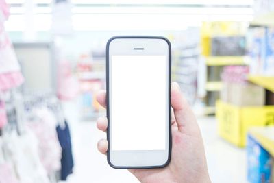 Cropped hand holding smart phone in supermarket