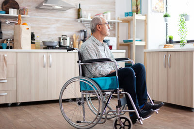 Side view of man sitting on table at home