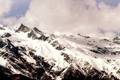 Snow covered mountains against cloudy sky