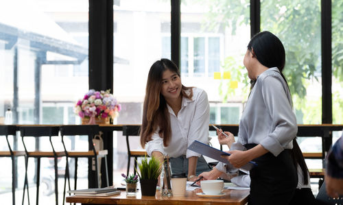 Women standing on table with people in background