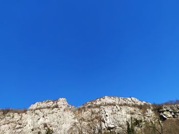 Low angle view of rock formations against clear blue sky