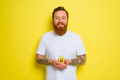 Man holding yellow mask against gray background