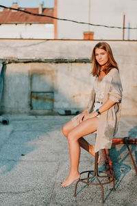 Portrait of smiling young woman sitting on stool