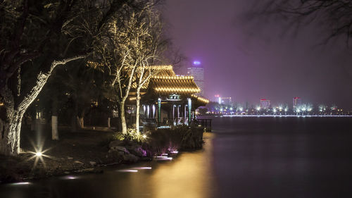 Illuminated building by river at night