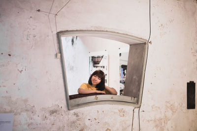 Portrait of woman sitting on window