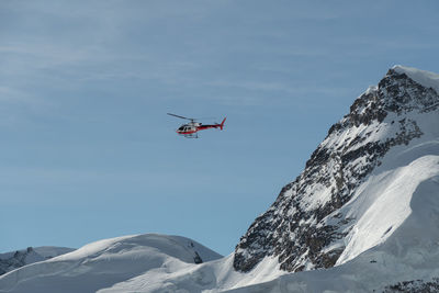 Jungfraujoch, canton bern, switzerland, february 11, 2023 helicopter is flying along the mountains