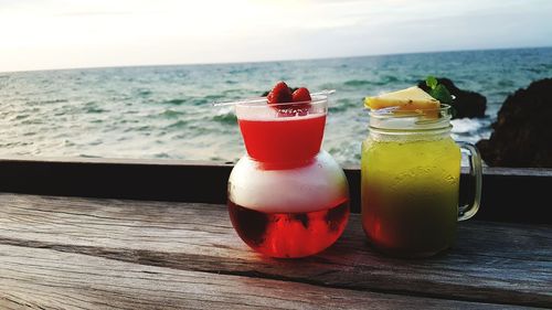 Close-up of drink on table by sea against sky