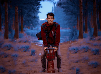 Full length portrait of young man standing against trees