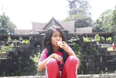 Portrait of young woman sitting on railing