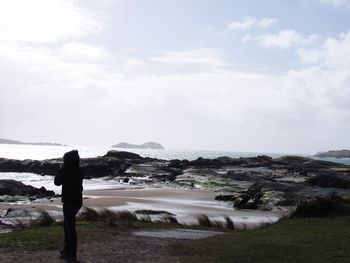 Woman standing on beach against sky