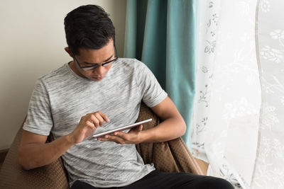 Young man using mobile phone at home