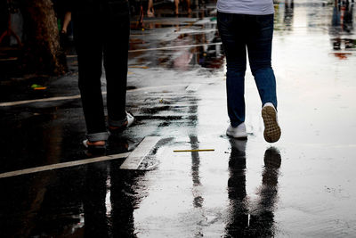 Low section of man standing on wet street