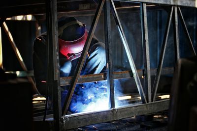 Worker welding metal in factory