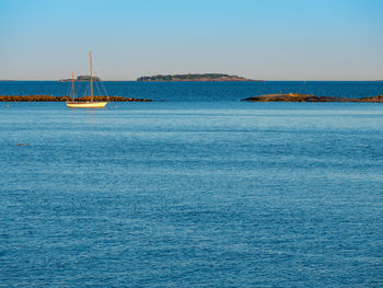 Sailboats in sea against clear blue sky