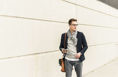 Young businessman walking in the street, carrying digital tablet and ear phones on the move