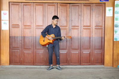 Full length of a smiling young man playing piano