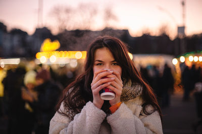 Happy teenage girl drinking mulled wine in christmas market in city