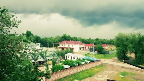 Houses by trees against sky