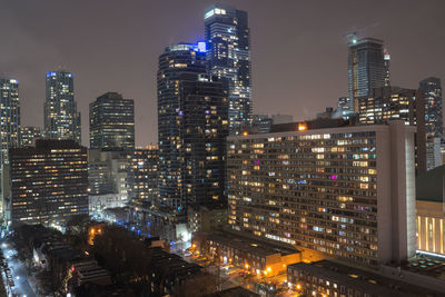 Illuminated buildings in city against sky at night