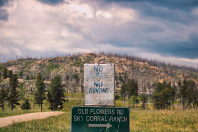 Information sign on field against sky