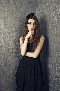 Portrait of young woman standing against wall