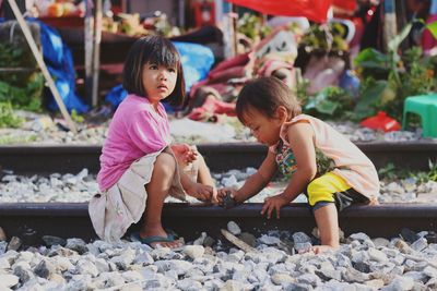 Full length of brother and sister playing on railroad track