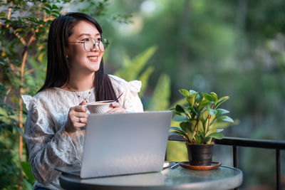 Smiling woman holding coffee cup sitting at cafe