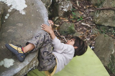 Little boy climbing a boulder outdoors