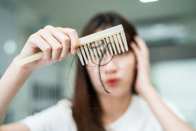 Asian woman have problem with long hair loss attach to comb brush.