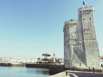 French flag on tower at harbor against sky