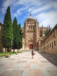 Woman walking in historic building against sky