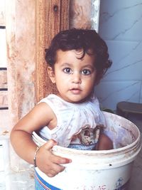 Portrait of baby girl sitting in bucket