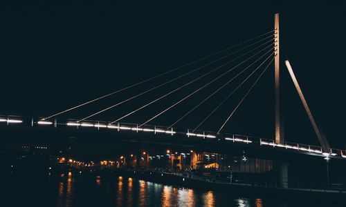 Low angle view of bridge over river against sky at night