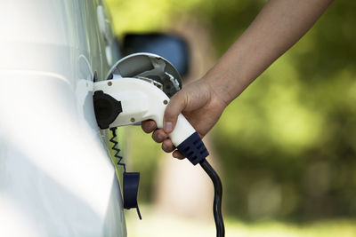 Cropped hand charging car at station